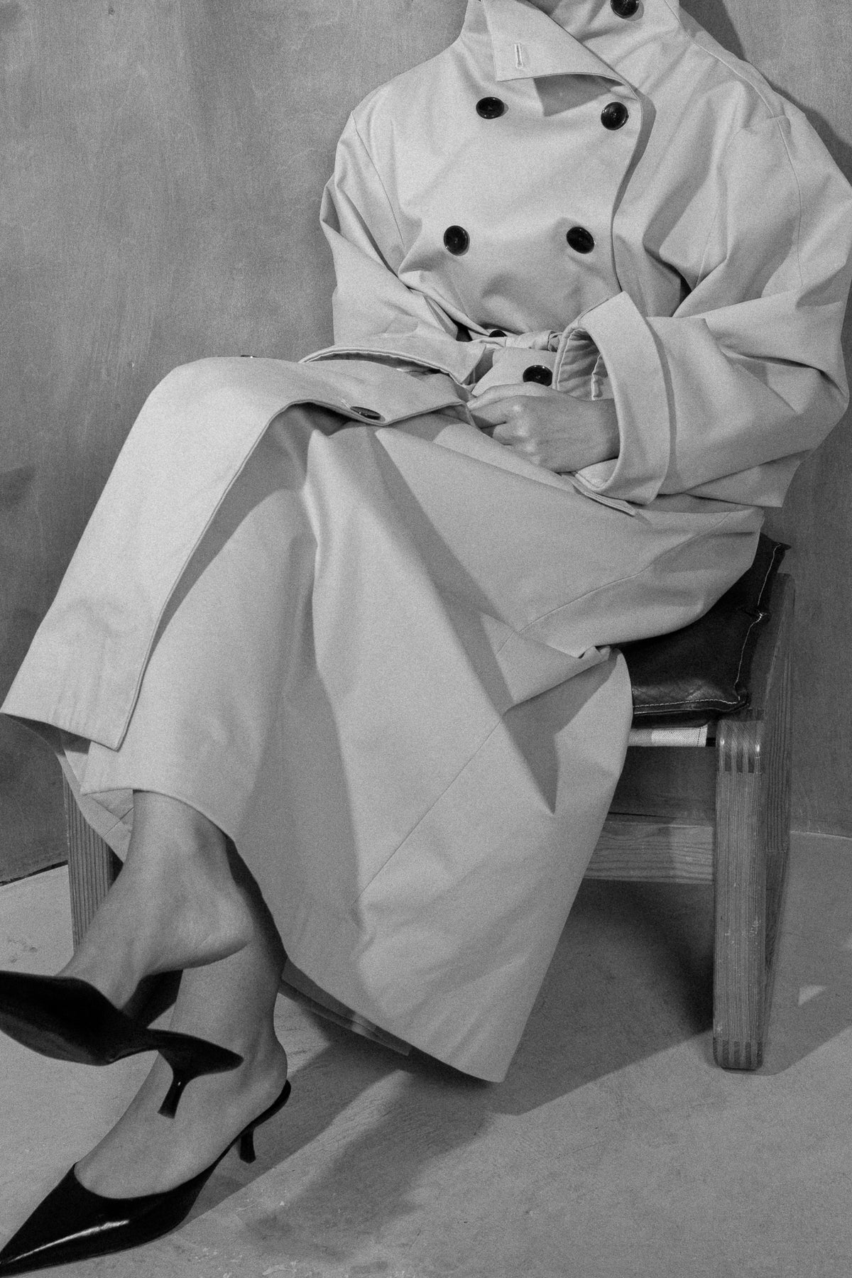 Dune gabardine trench coat, seated on a wooden chair