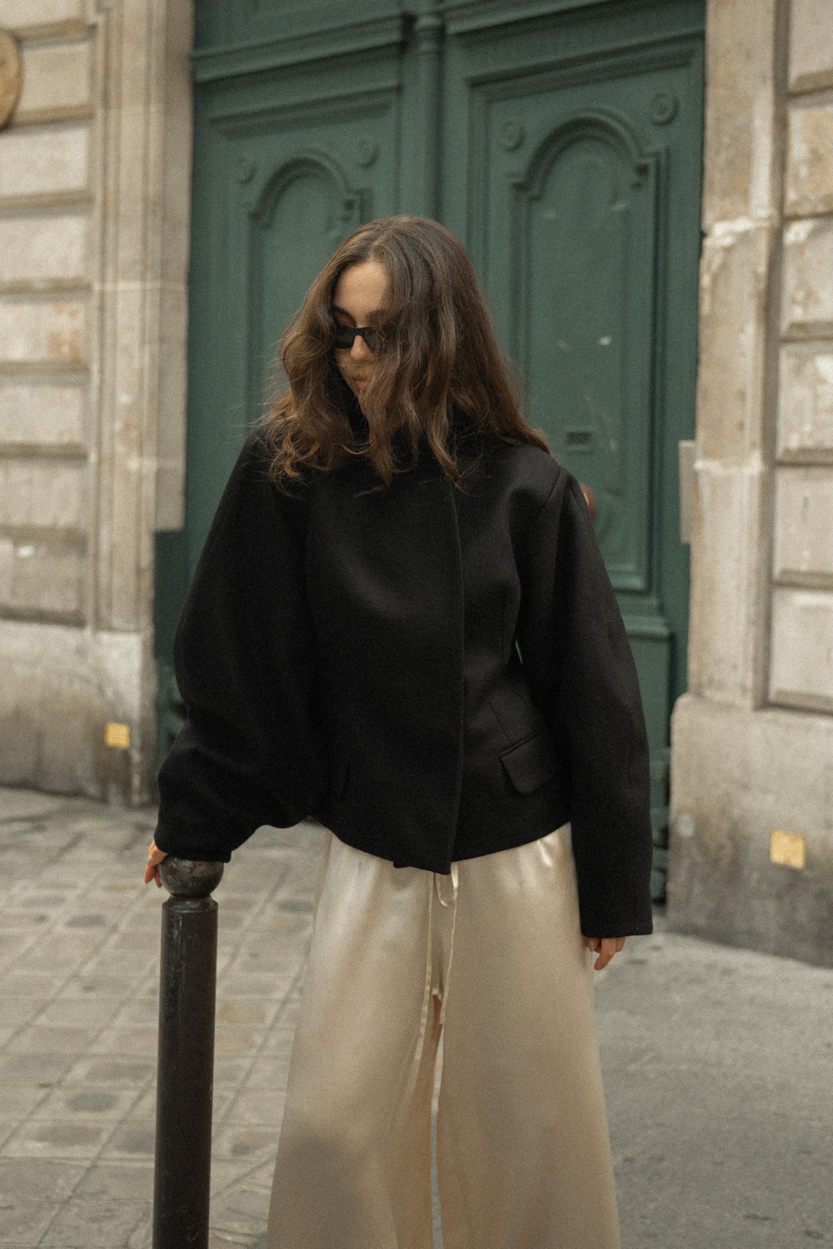 Fitted balloon-sleeve wool jacket in black, with champagne silk trousers on a Paris street