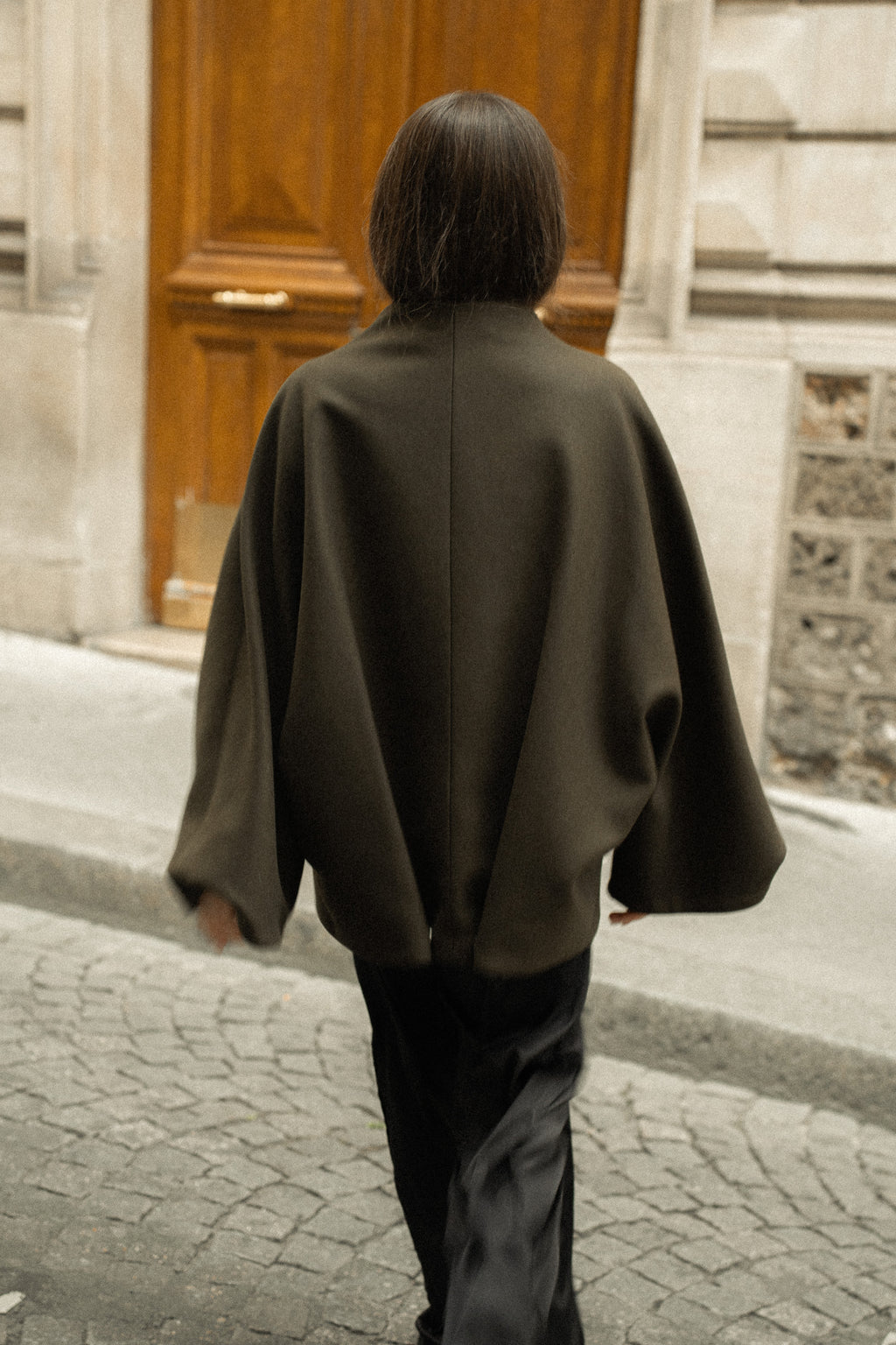 Kimono convertible en laine, teinte mousse, dans une rue de Paris, vue de dos